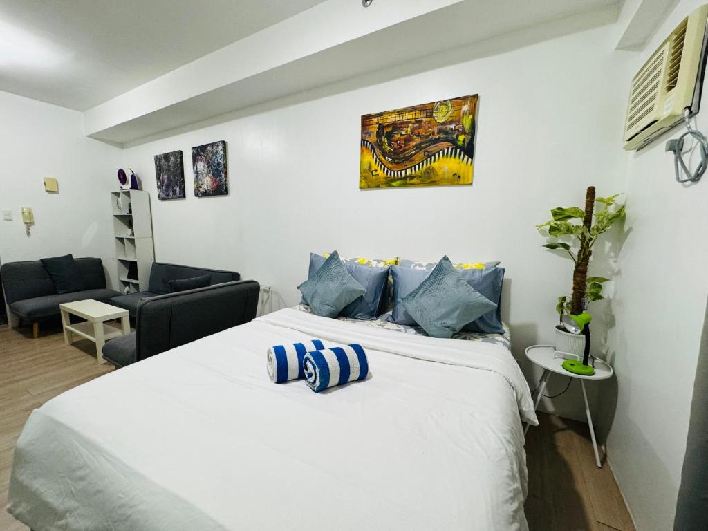 a bedroom with a large white bed with blue pillows at Vinia Infinity Studio 1 Near Malls with WiFi and Netflix in Manila