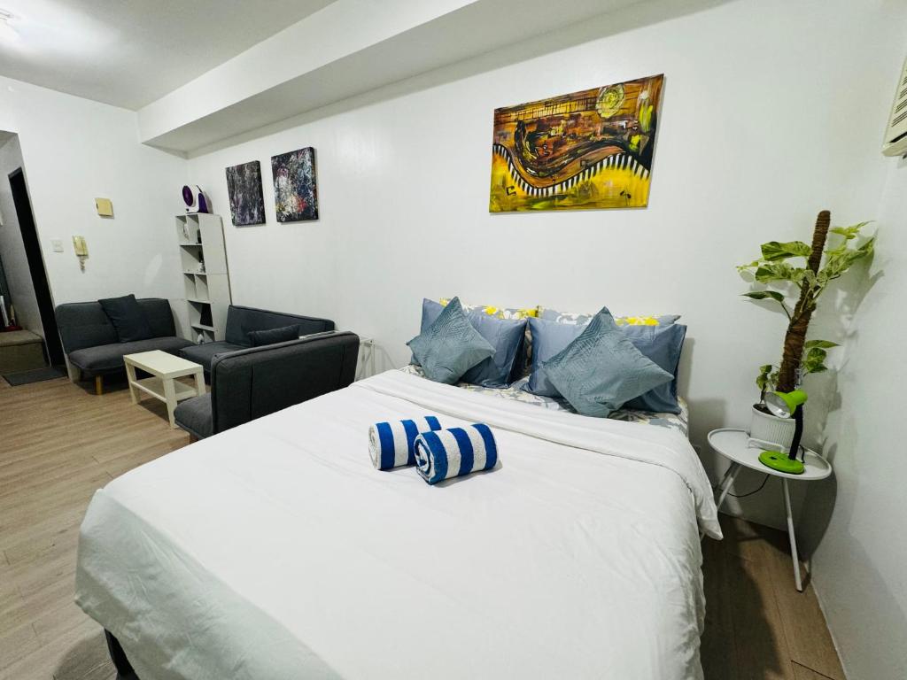 a bedroom with a large white bed with blue pillows at Vinia Infinity Studio 1 Near Malls with WiFi and Netflix in Manila
