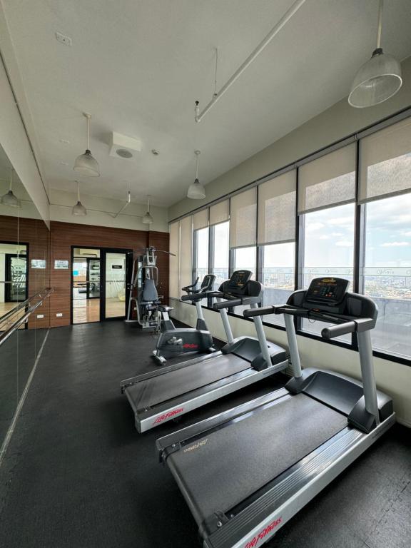 a gym with a row of treadmills and windows at Vinia Infinity Studio 1 Near Malls with WiFi and Netflix in Manila