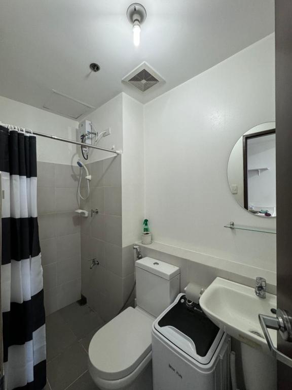 a bathroom with a toilet and a sink and a mirror at Vinia Infinity Studio 1 Near Malls with WiFi and Netflix in Manila