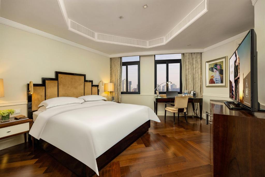 a bedroom with a large white bed and a desk at Jinjiang Metropolo Hotel Classiq,Shanghai Bund Circle in Shanghai