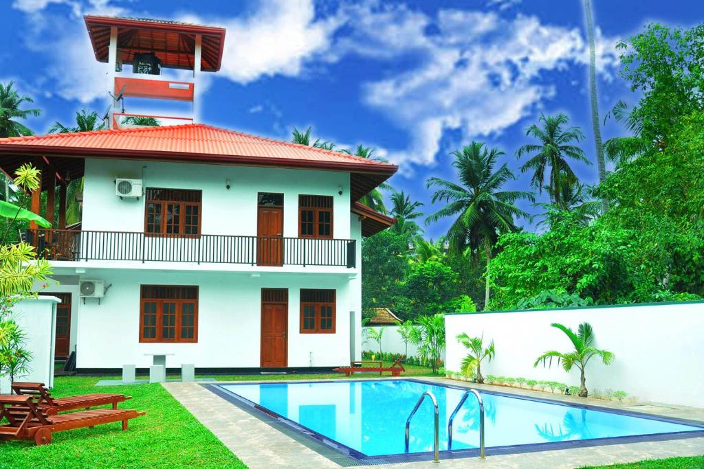 a villa with a swimming pool in front of a house at Hannaford House Bentota in Bentota