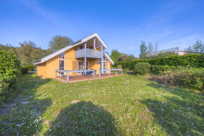 ein kleines gelbes Haus mit Balkon auf einem Hof in der Unterkunft Seeschwalbe Classic 58 in Rechlin