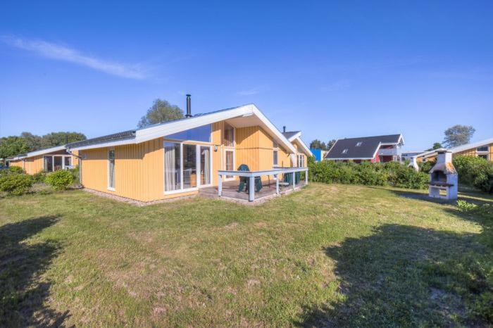 a small yellow house on a grass field at Seeschwalbe 69A in Rechlin
