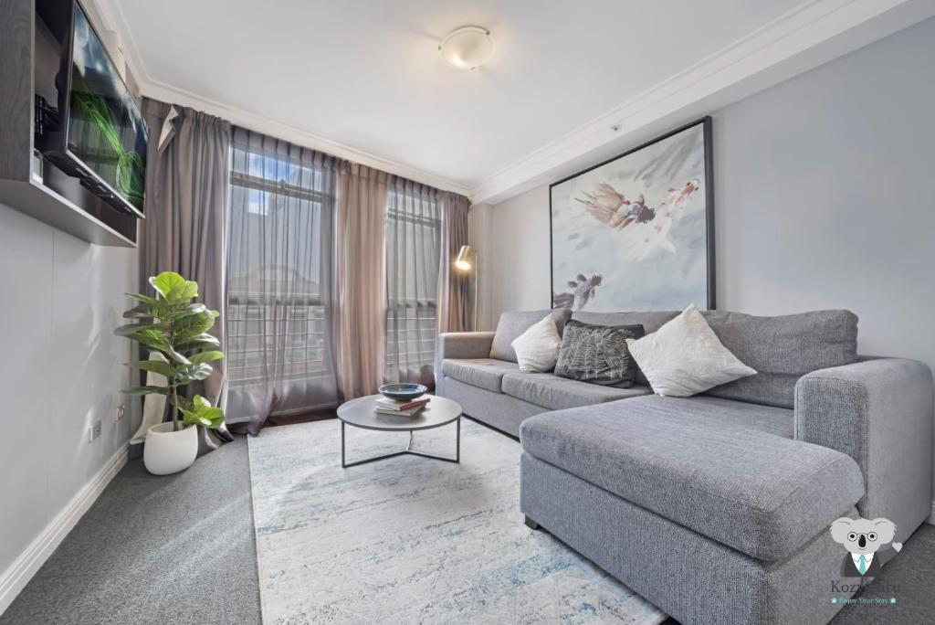 un salon avec un canapé et une télévision dans l'établissement KozyGuru | Sydney CBD | Amazing 2 Bed Family Apt, à Sydney