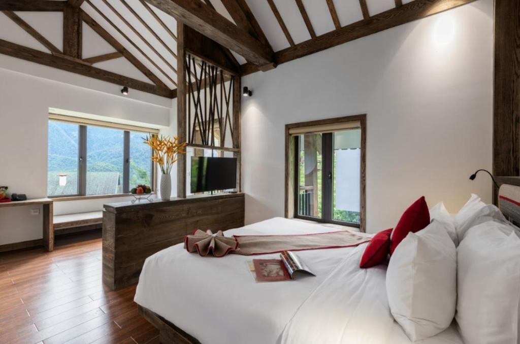 a bedroom with a large white bed and windows at Sapa Catcat Hills Resort & Spa in Sa Pa