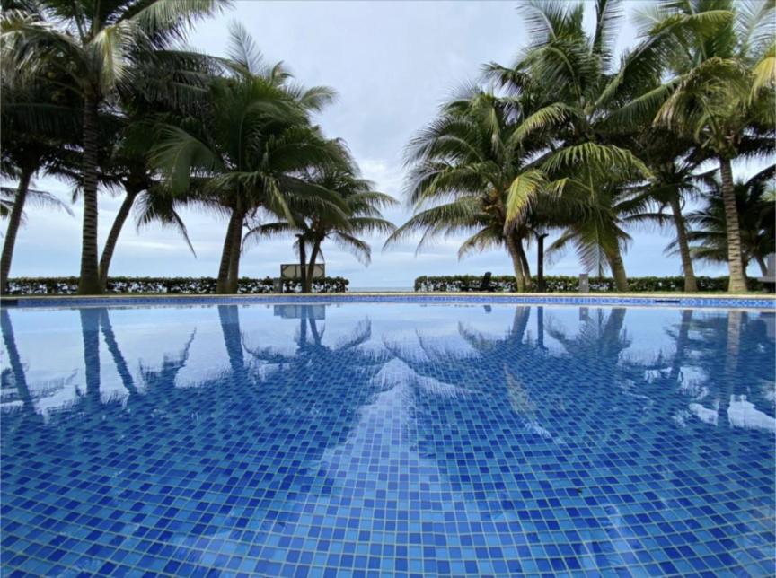 a blue swimming pool with palm trees in the background at Agradable estancia en Monterrico in Monterrico