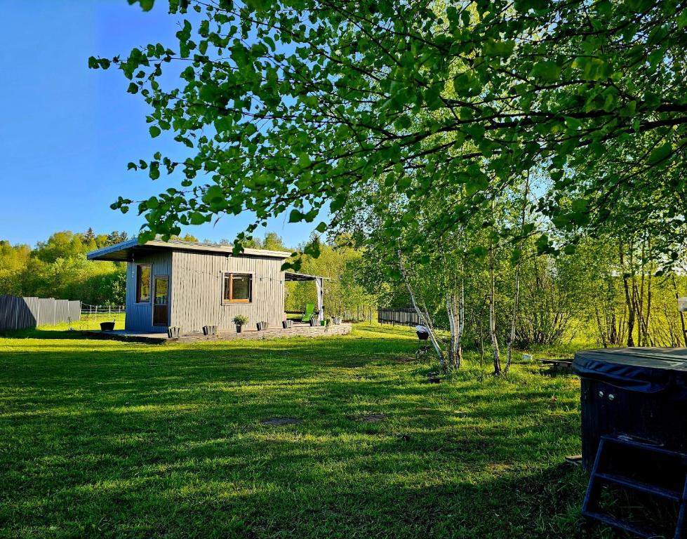 ein kleines Gebäude auf einem Grasfeld mit einem Baum in der Unterkunft Lāsītes in Lielvārde