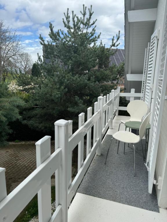 una valla blanca en un porche con sillas y un árbol en Suite avec balcon et lit Queen size, en Commugny