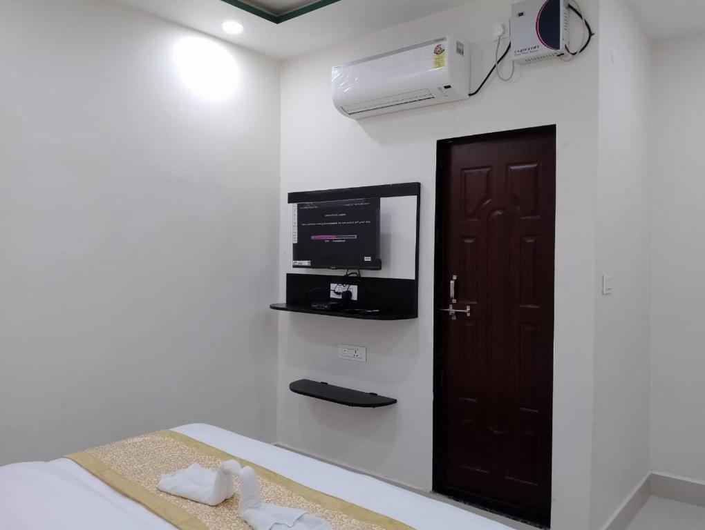 Habitación con cama, TV y puerta. en Hotel Aastha Inn, en Varanasi