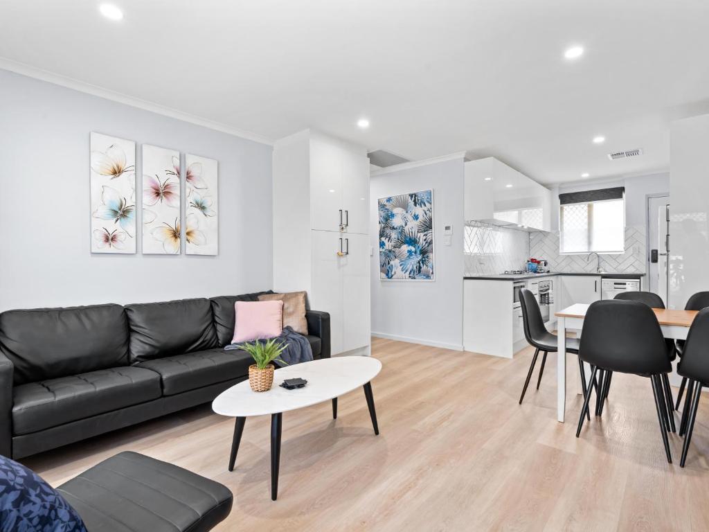 a living room with a black couch and a table at Hectorville Luxe Haven Suite in Campbelltown