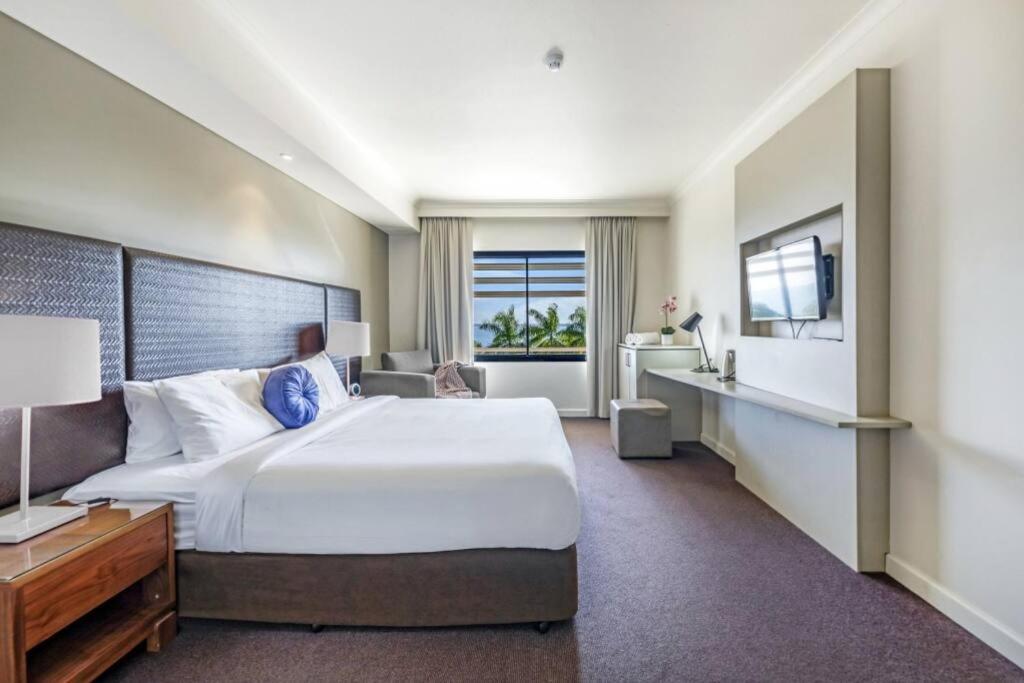 a hotel room with a large bed and a television at An Exceptional Seaside Esplanade Locale with Pool in Darwin