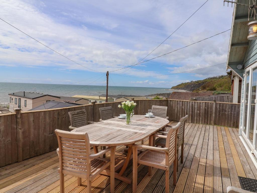 a wooden table and chairs on a deck with the ocean at Ammonite in Lyme Regis