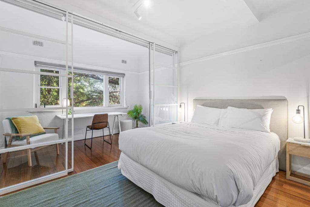 Habitación blanca con cama grande y escritorio. en Elegant 1-Bed CBD Apartment with Sunroom Study en Melbourne