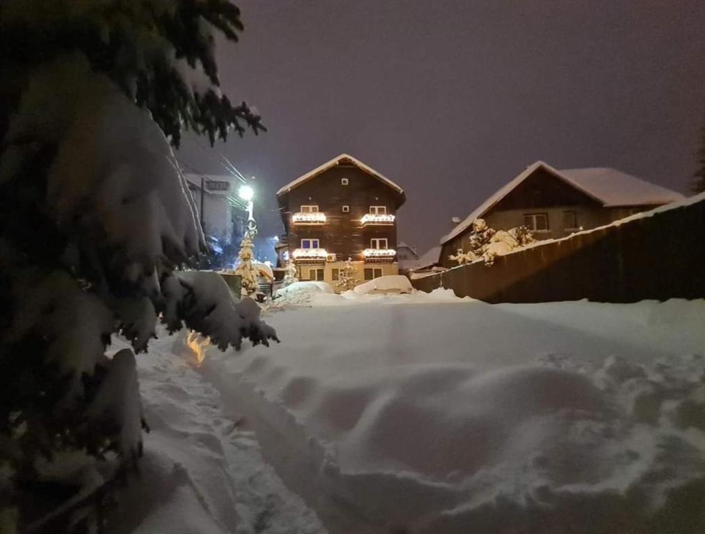 una casa está cubierta de nieve por la noche en Vila Șoimul Predeal en Predeal