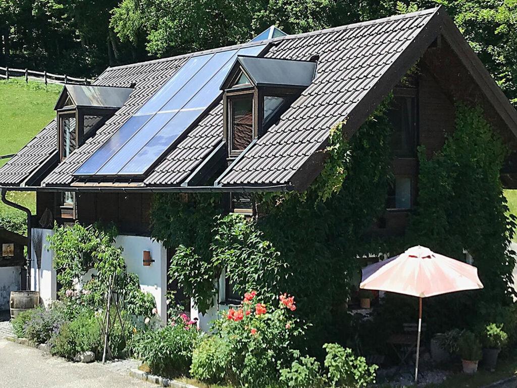 ein Haus mit einem Sonnendach mit einem Regenschirm in der Unterkunft Bergwiesen - Studio House 