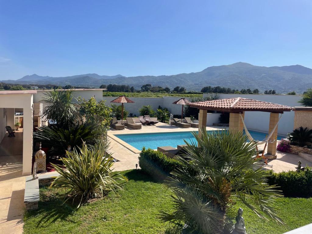 een resort met een zwembad en uitzicht op het water bij Chambre d’hôtes Corse Villa Anna in Vescovato
