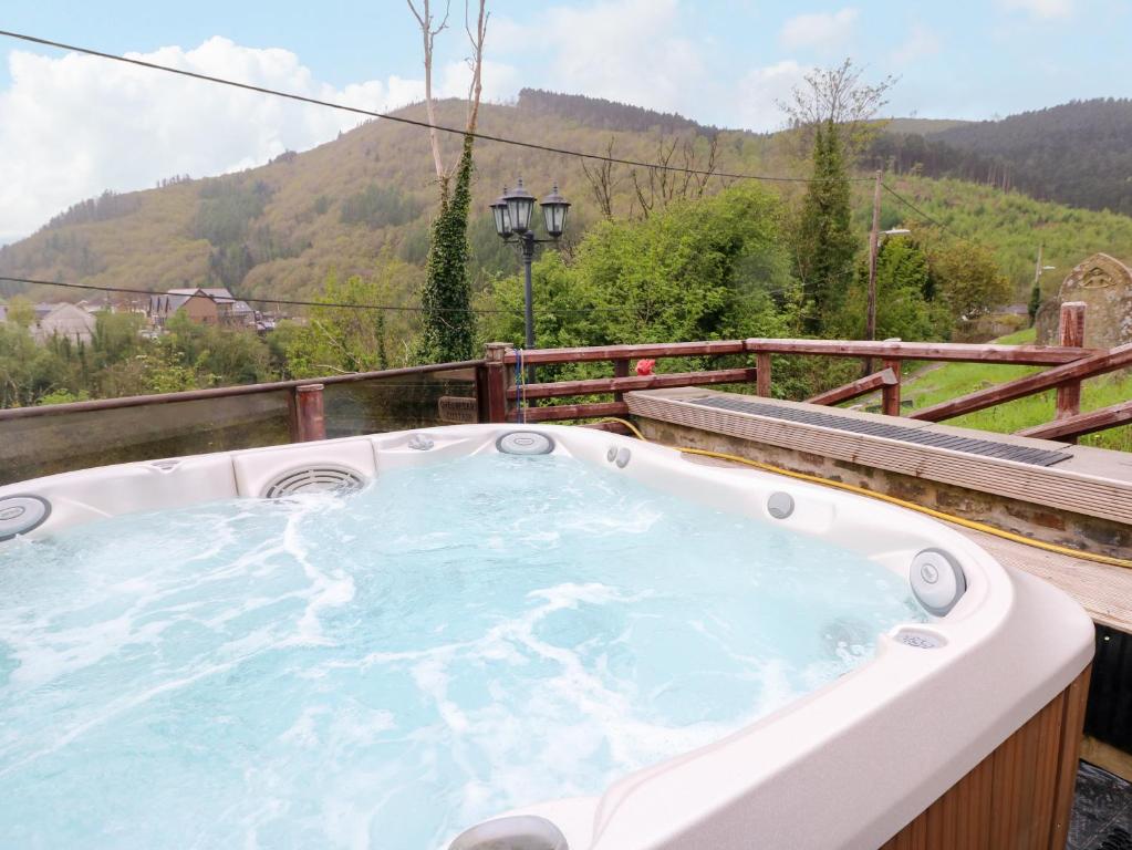 une baignoire jacuzzi avec vue sur la montagne dans l'établissement Greenheart Cottage, à Port Talbot
