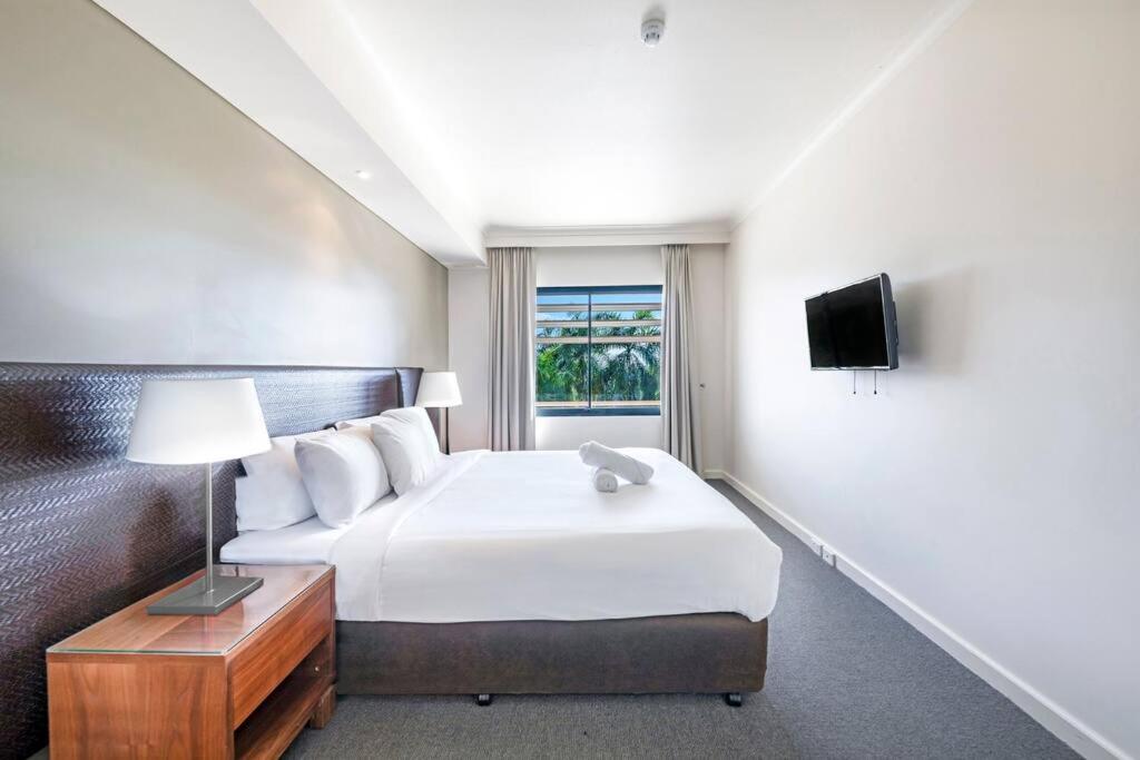 a hotel room with a bed and a television at Idyllic Waterfront Pool Escape with Esplanade View in Darwin