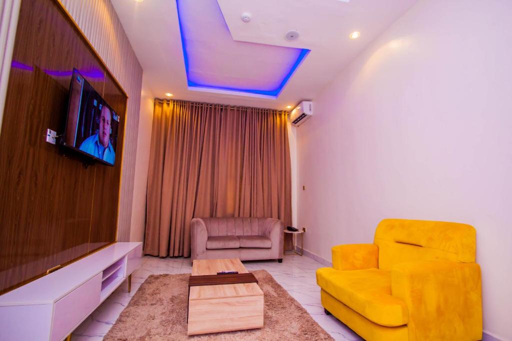 a living room with a yellow couch and a tv at Soulmate Hotels & Suites in Lagos