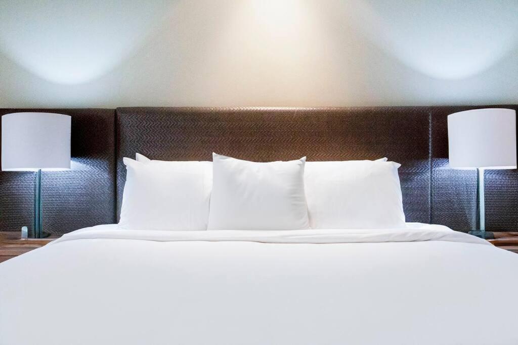 a large bed with white pillows and two lamps at Idyllic Waterfront Pool Escape with Esplanade View in Darwin