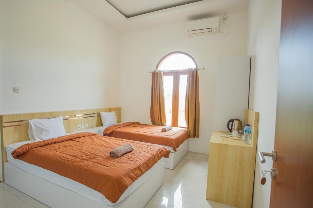 1 dormitorio con 2 camas y ventana en De Luna Guest House, en Kuripan
