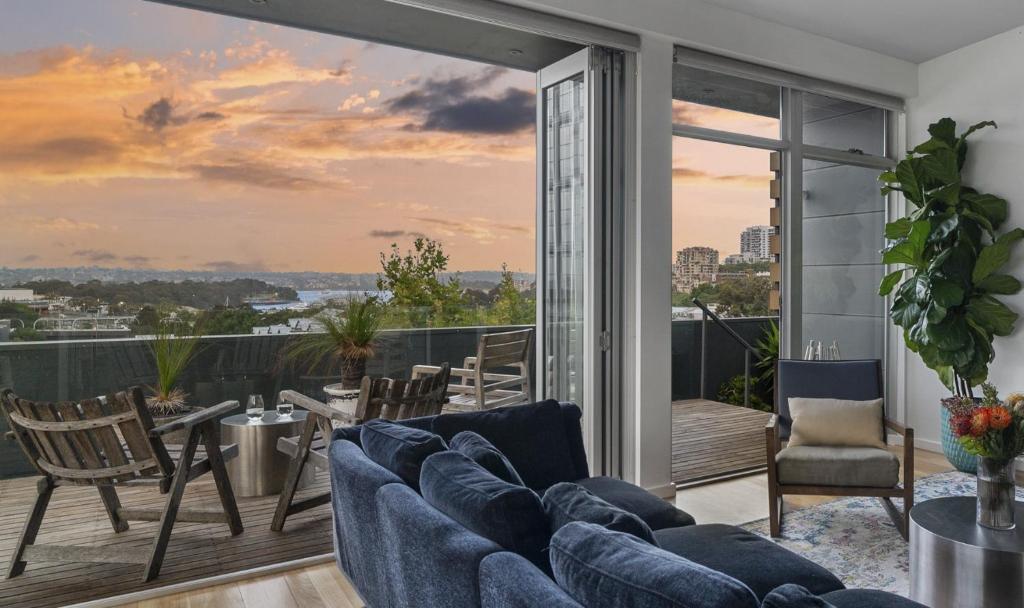 a living room with a couch and a balcony at Sydney Penthouse in Sydney