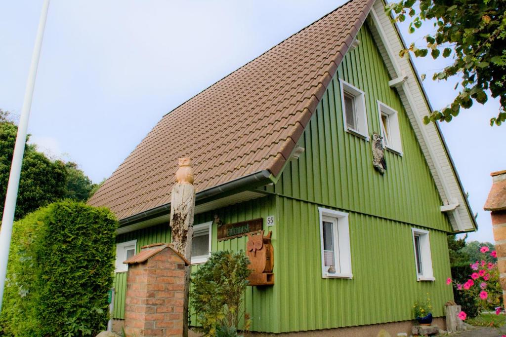 uma casa verde com telhado castanho em Ferienhaus Eulennest - Ulenhoef em Prerow