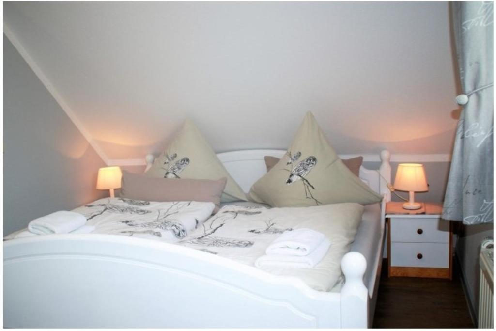 FeWo Waldkauz - Ulenhoef في بريرو: سرير أبيض في غرفة بها مصباحين