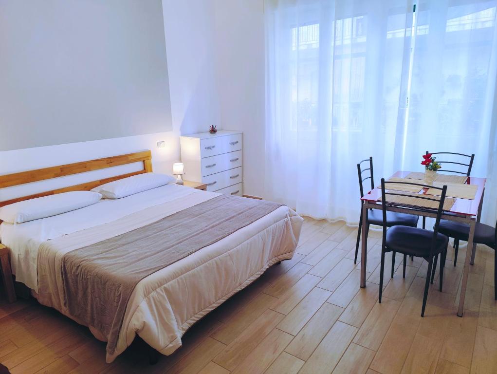 a bedroom with a bed and a table and a desk at B&B Vento Aureo Rooms in Milazzo