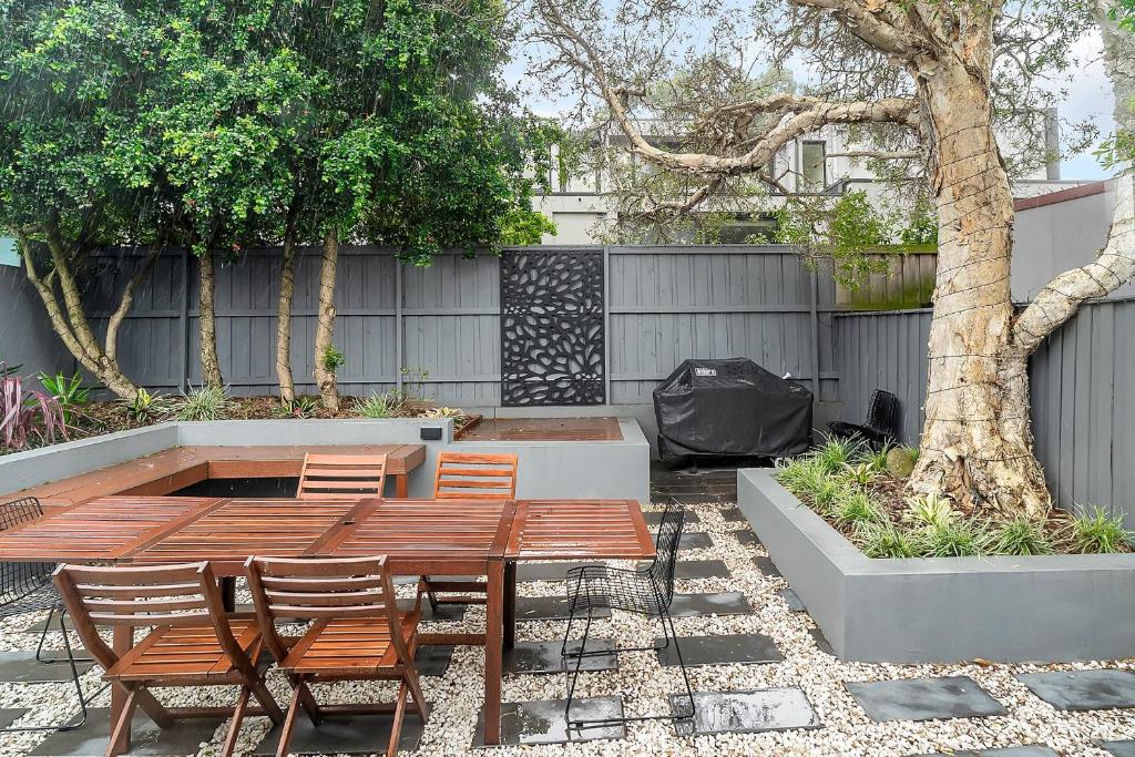 un patio con mesa, sillas y un árbol en Balmain Beauty - Spacious Garden en Sídney