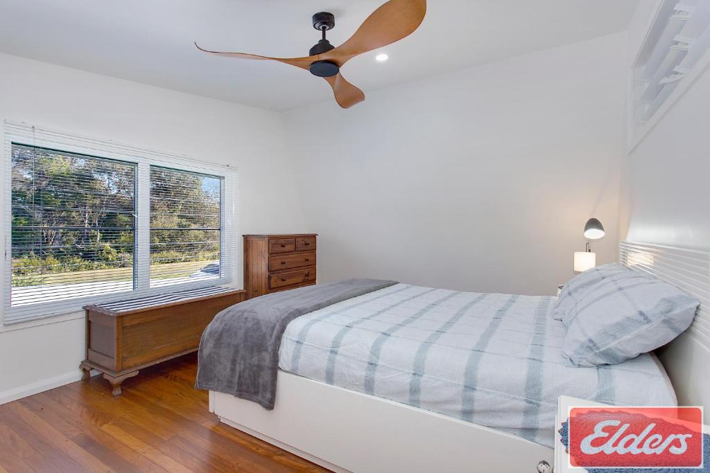 um quarto com uma ventoinha de tecto e uma cama em Dreamtime - 5 Ward St Hat Head NSW 2440 em Hat Head