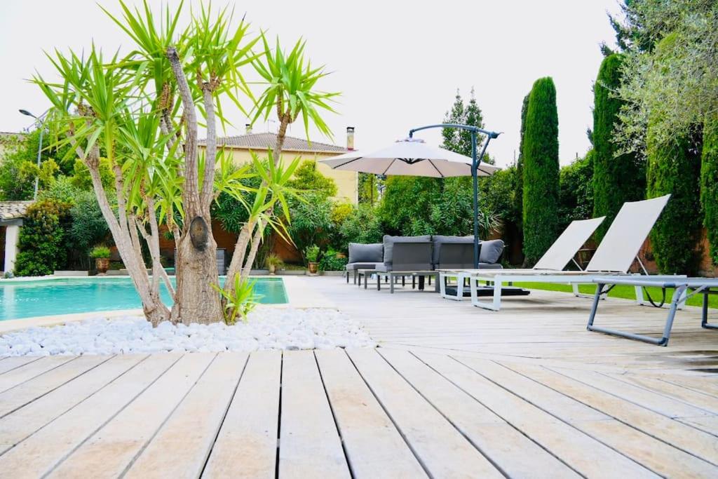 une terrasse avec des chaises et un parasol ainsi qu'une piscine dans l'établissement Maison d'Architecte * 2 piscines *, à Saint-Saturnin-lès-Avignon