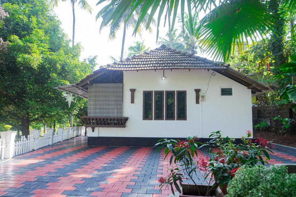 a small white house with a red brick patio at Sanctuary View Homestay Thattekad in Ernakulam