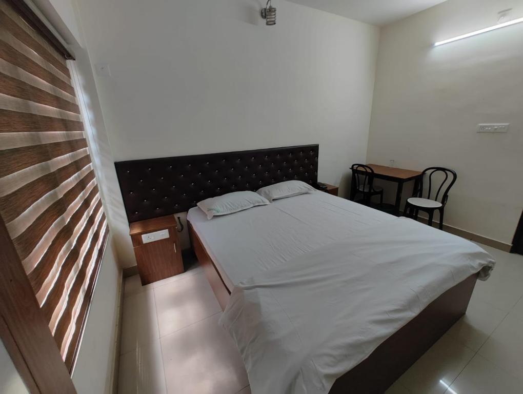 1 dormitorio con 1 cama, mesa y sillas en Thampanoor Tourist Home en Thiruvananthapuram