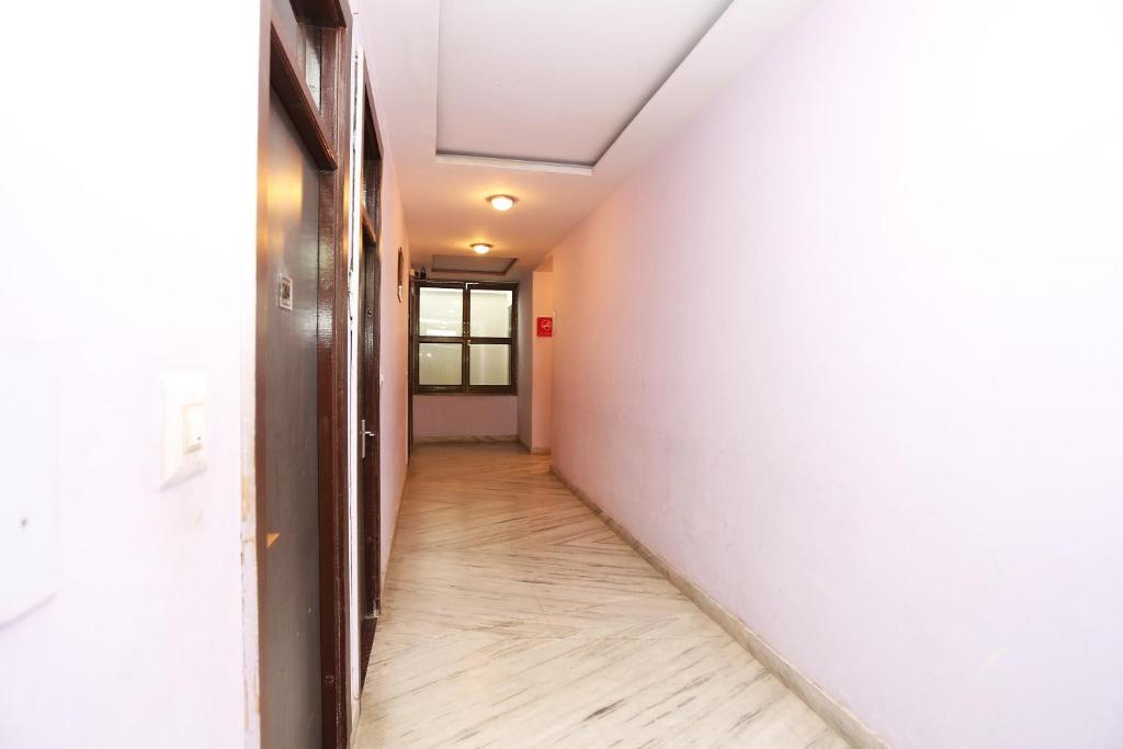einen leeren Flur mit einer weißen Wand und einem Holzboden in der Unterkunft OYO Hotel Kanha Palace in Kota