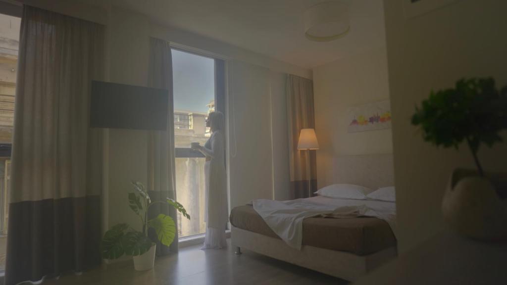 um quarto com uma cama e uma grande janela em Tins Hotel City - Athens em Atenas