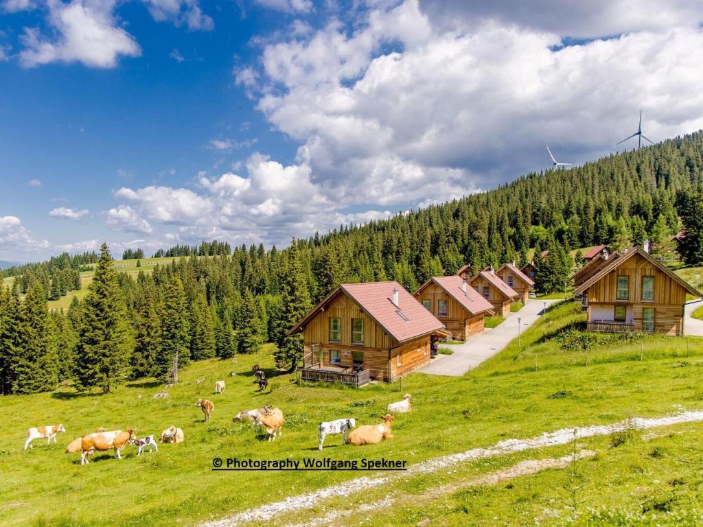 eine Kuhherde, die auf einem Feld mit Häusern weidet in der Unterkunft Beautiful Holiday Home in Weinebene with Sauna in Posch Alpe