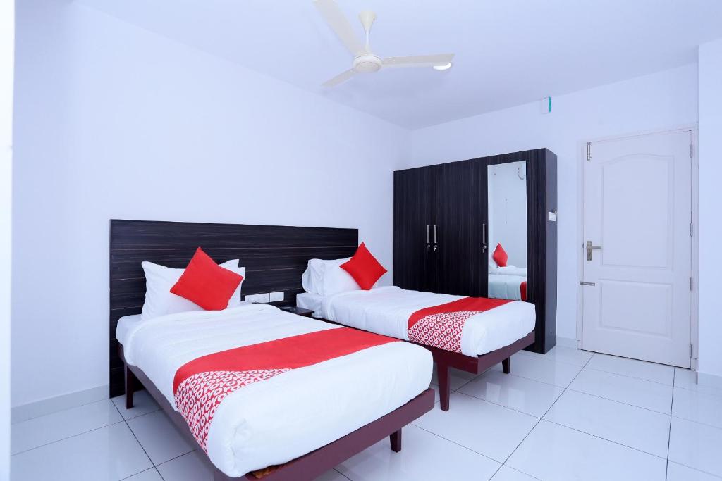 two beds in a room with red and white pillows at Kings Fort in Cochin