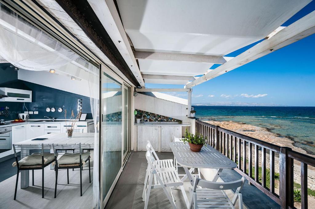 een balkon met een tafel en stoelen en de oceaan bij Casa Cinzia in Marzamemi
