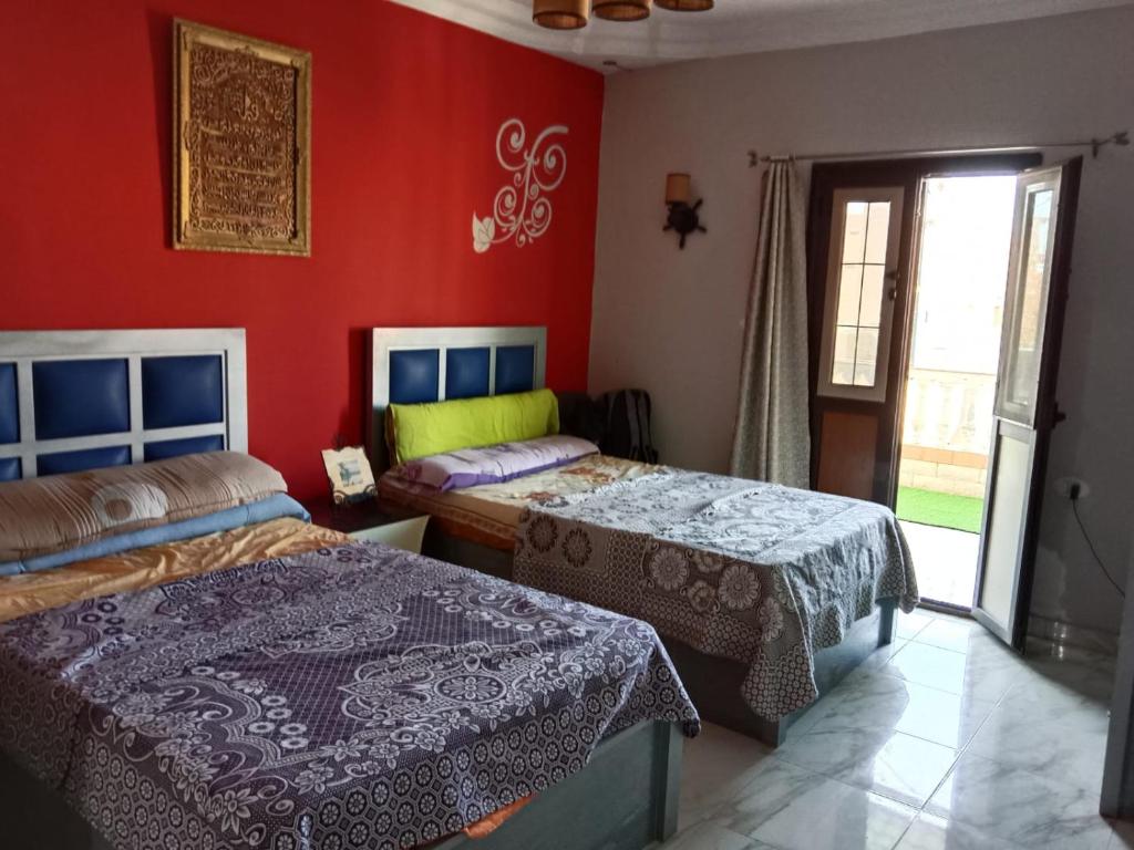 two beds in a room with red walls at Marsa Matrouh in Marsa Matruh