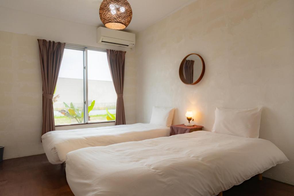 two beds in a hotel room with a window at the Sanctuary Kohama Retreat in Kohama