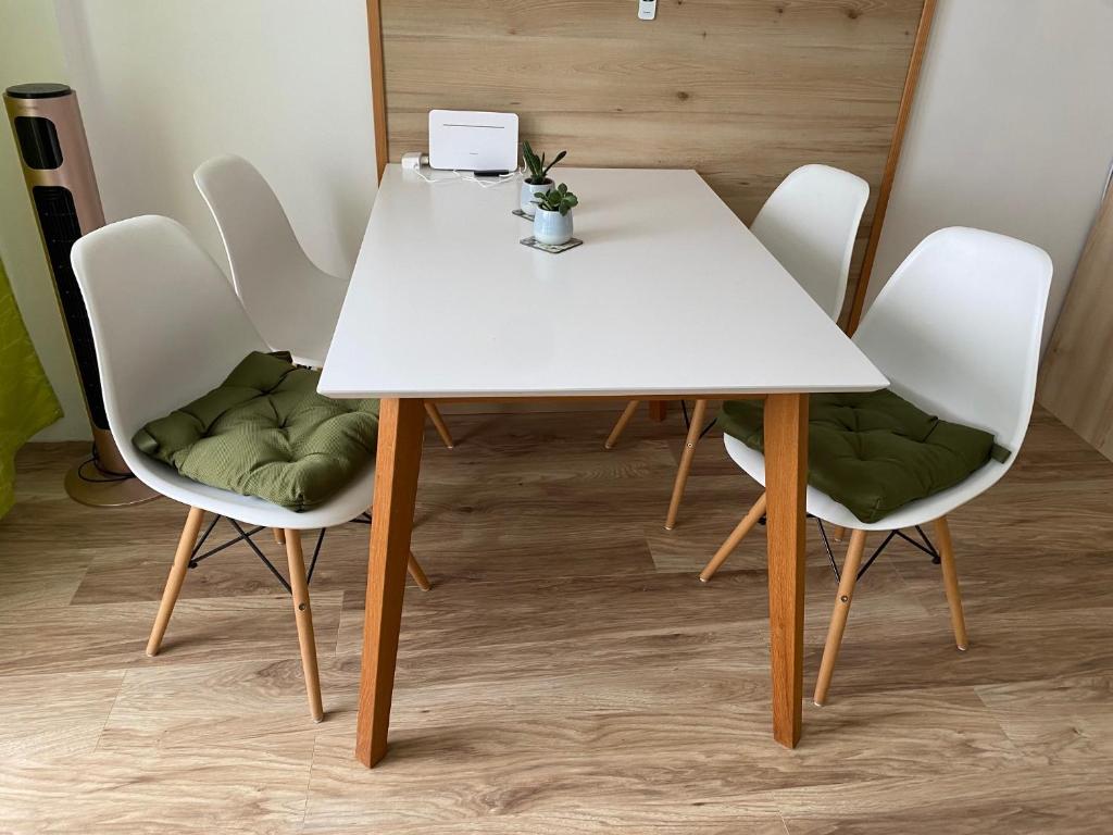 a table and chairs with a white table and green cushions at Apartment mit Seeblick in Strobl