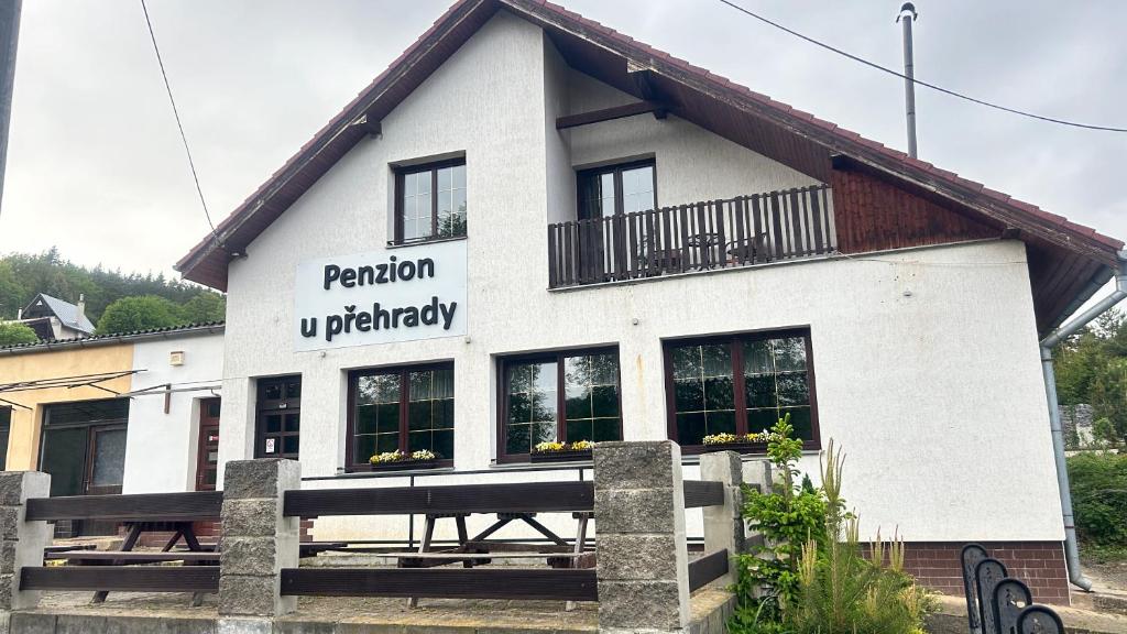 een wit gebouw met een bord aan de zijkant bij Penzion u přehrady in Štěchovice