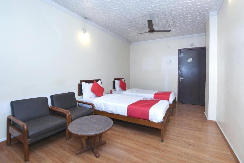 a hotel room with a bed and a chair at Capital O Hotel Kartik in Jabalpur