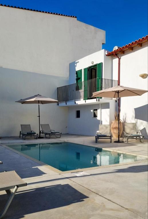 a swimming pool with two umbrellas next to a building at Traditional Anna's Stone House with Private Pool in Margarítai