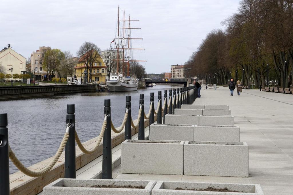 une passerelle à côté d'une rivière avec un bateau dans l'établissement Danes Square apartments with River View, à Klaipėda