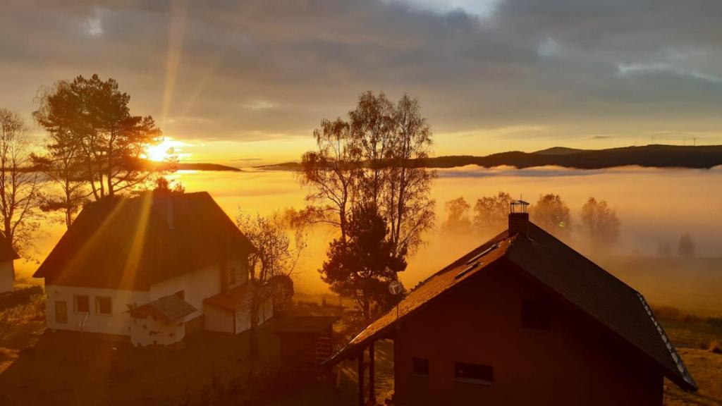 an image of a sunrise over a foggy field with houses at Chata OSTRUZINA 9 in Lipno nad Vltavou