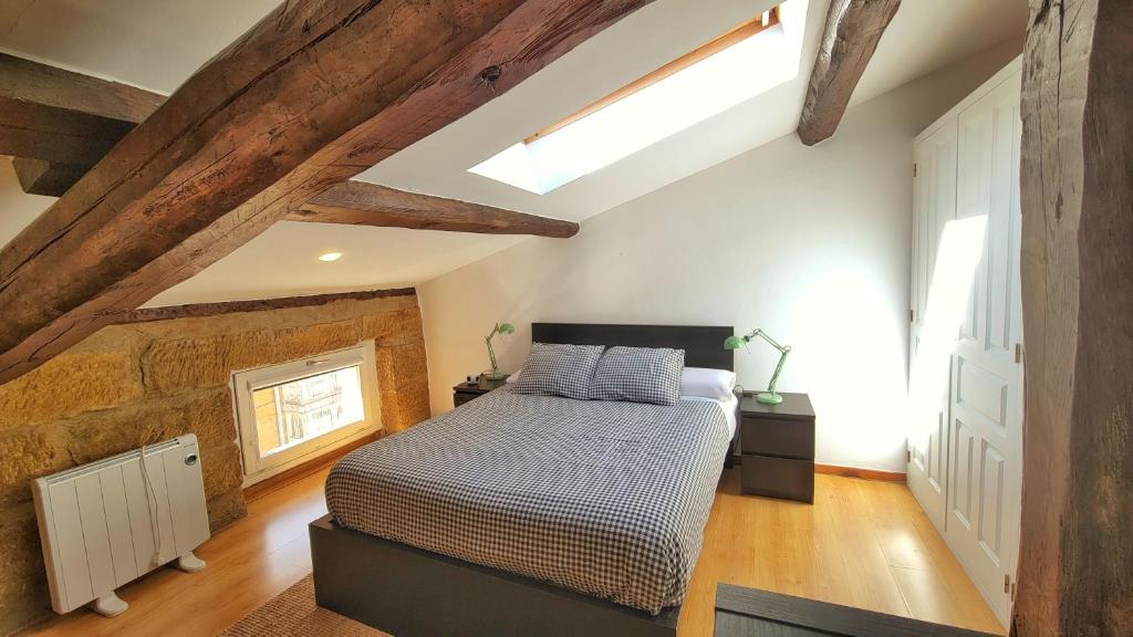 1 dormitorio con 1 cama en una habitación con techos de madera en Buhardilla céntrica para parejas, en Haro