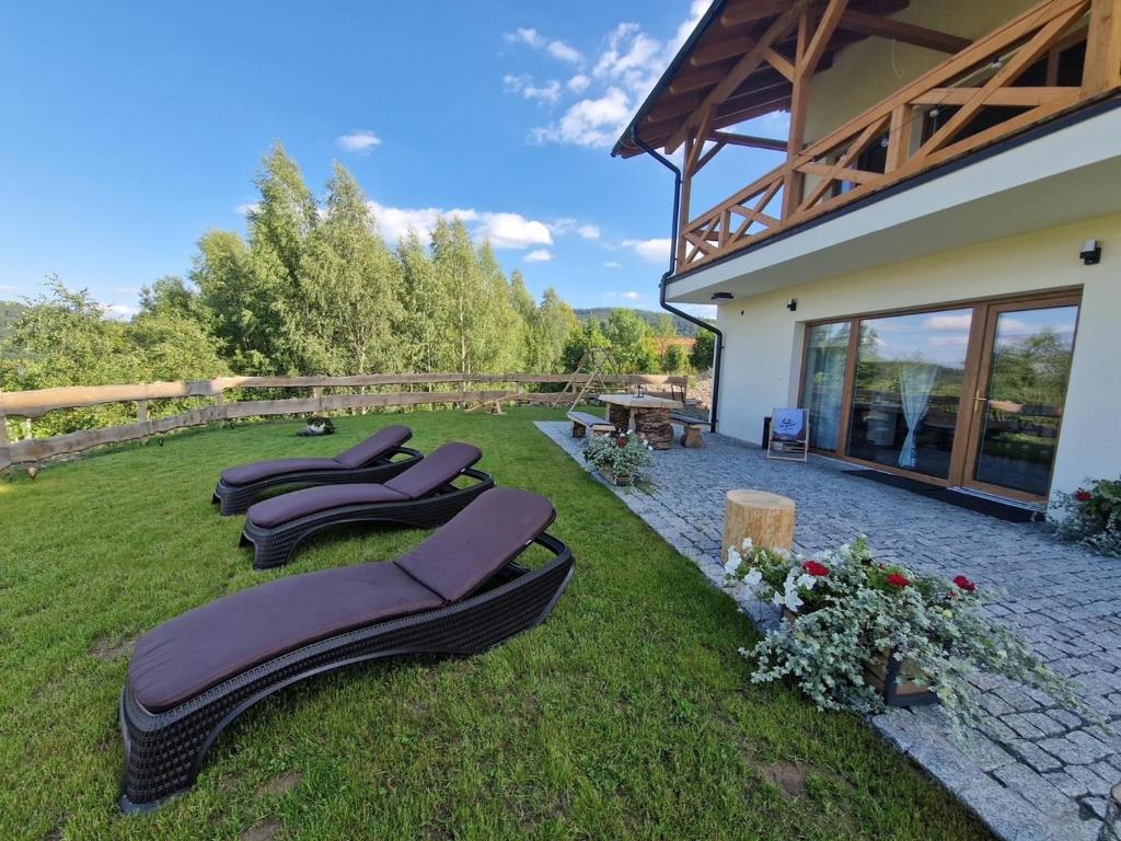 a row of chaise lounges on the grass near a house at Dusznickie Apartamenty z widokiem in Duszniki Zdrój